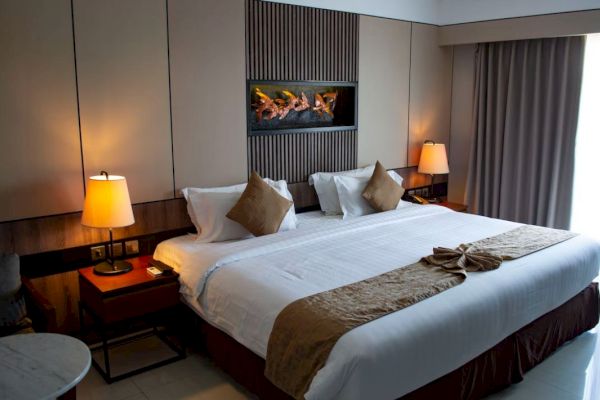 A neatly arranged hotel room with a large bed, brown accents, and warm lighting from bedside lamps, creating a cozy atmosphere.