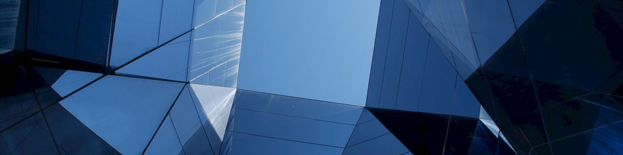 The image shows a geometric architectural structure with reflective glass panels forming a view of the sky through a central, open square.