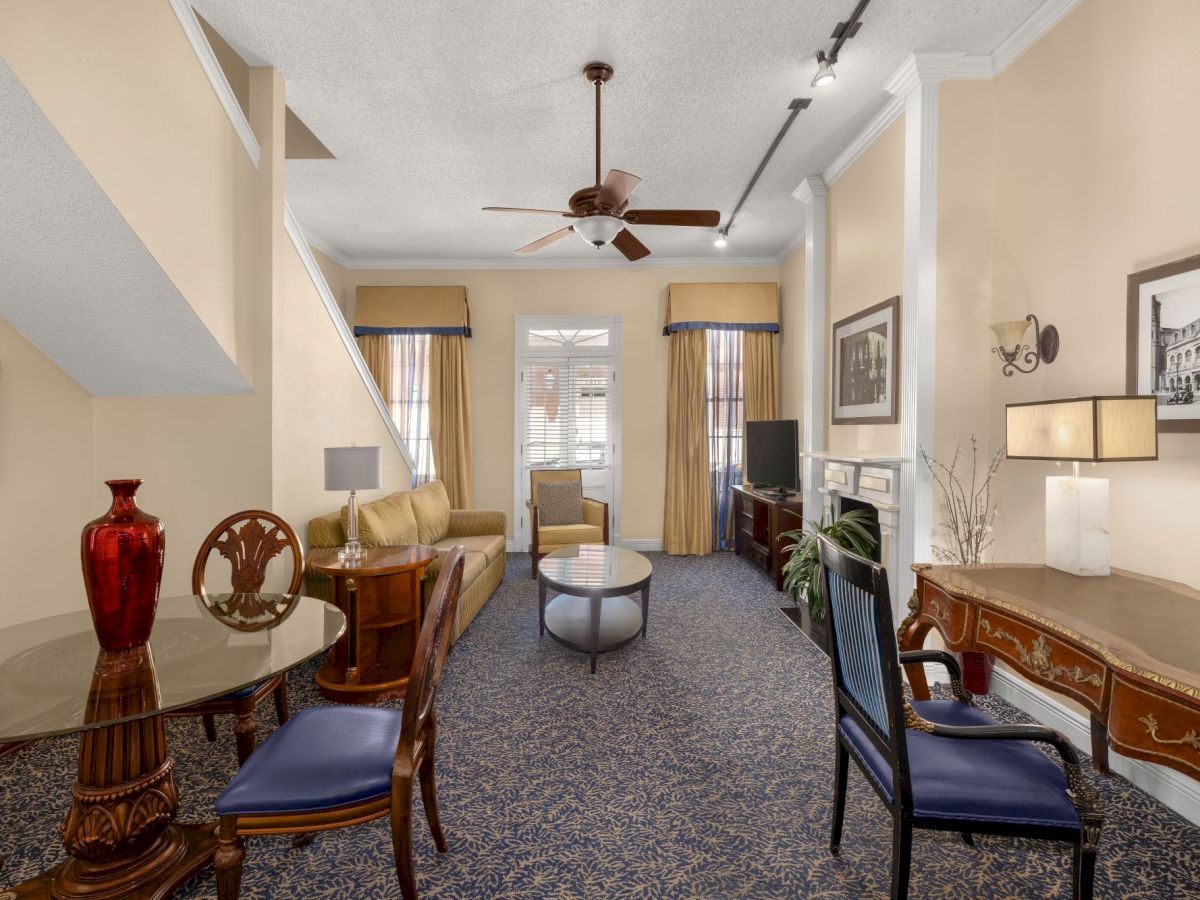 Elegant living room with blue patterned carpet, sofa, coffee table, ceiling fan, curtains, fireplace, and framed art.