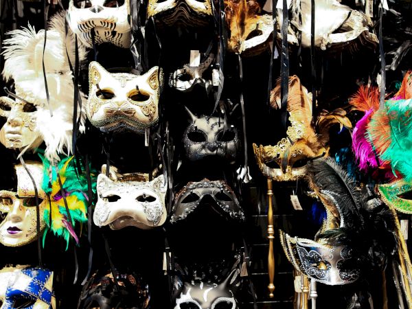 The image shows a display of various decorative masks with feathers and intricate designs, often worn for masquerade events.